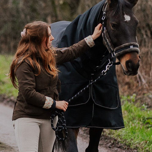 Woman walking a horse on a rural dirt path with cross section head collar and lead rope